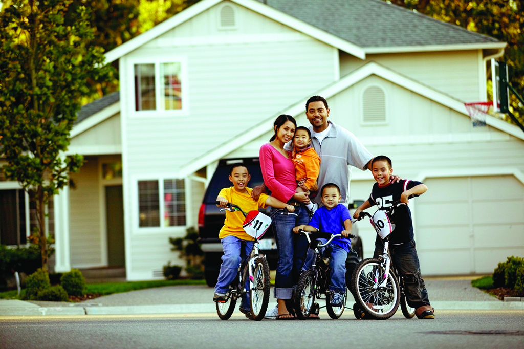 Couple with four kids, three kids on bikes outside house