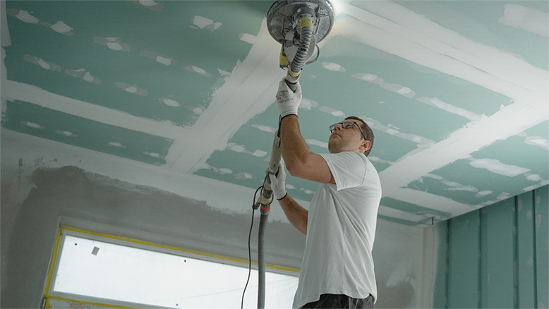 man painting room with a brush machine