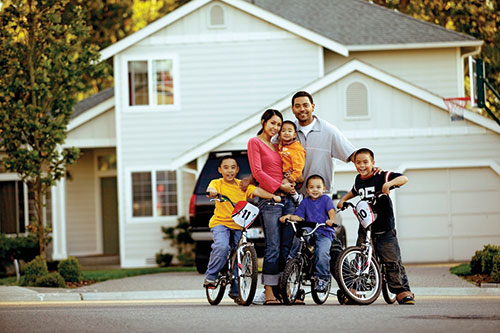 Couple with four kids, three kids on bikes outside house
