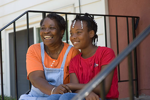 Woman and girl sitting on front steps with a black railing