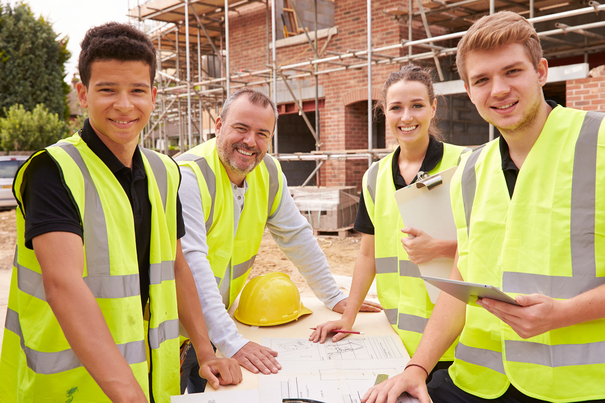 Three young people and an older mentor at a construction site