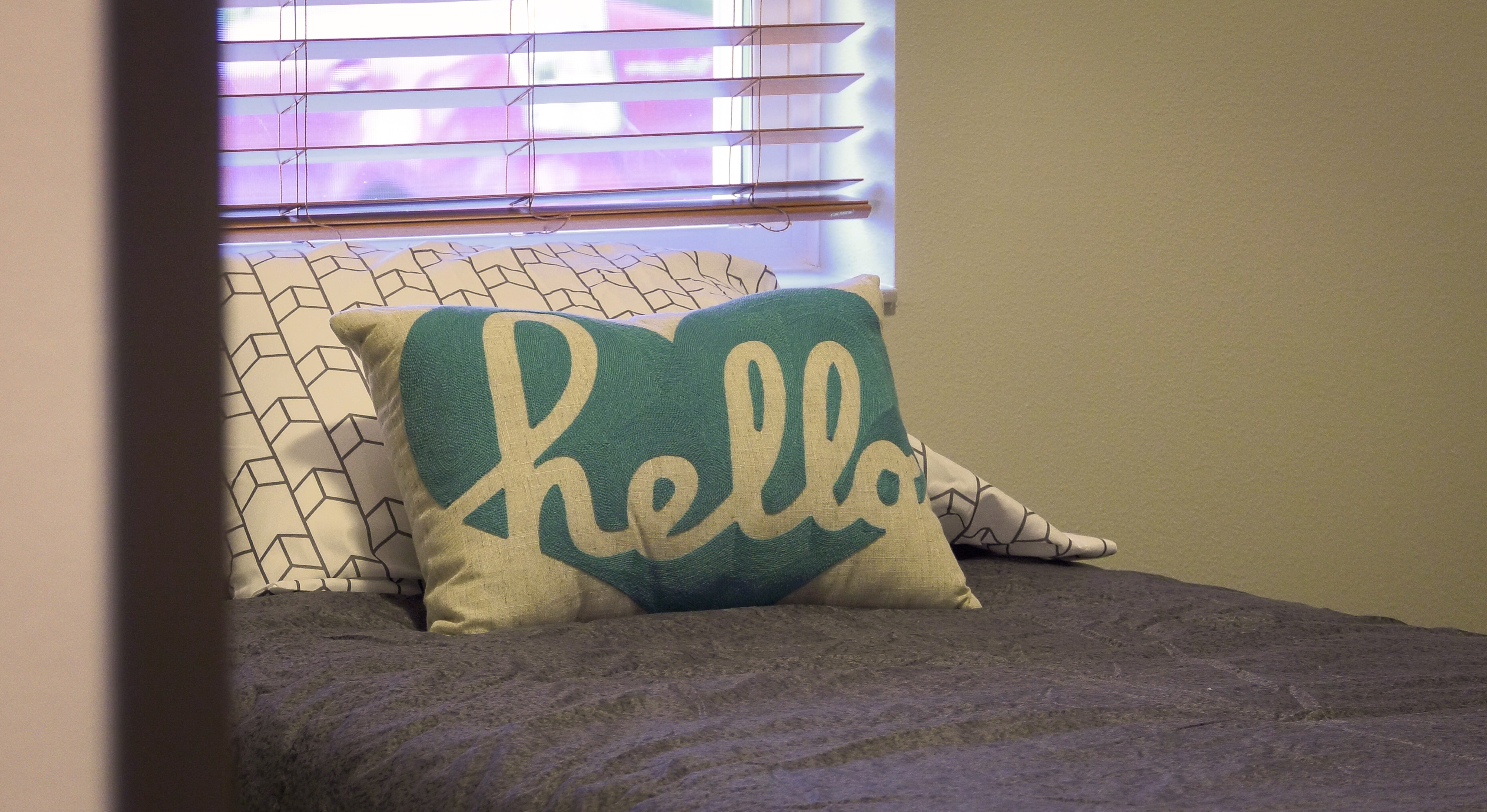 Bed with a turquoise hello pillow